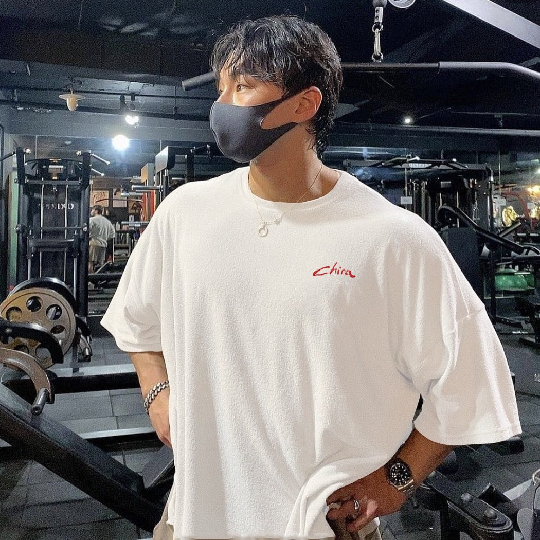 Ropa de entrenamiento muscular para hombre de manga corta de estilo chino, camiseta deportiva holgada versátil e informal con hombros caídos y media manga.